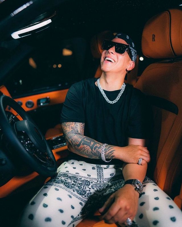 daddy yankee wearing black tee and white with black design joggers.
